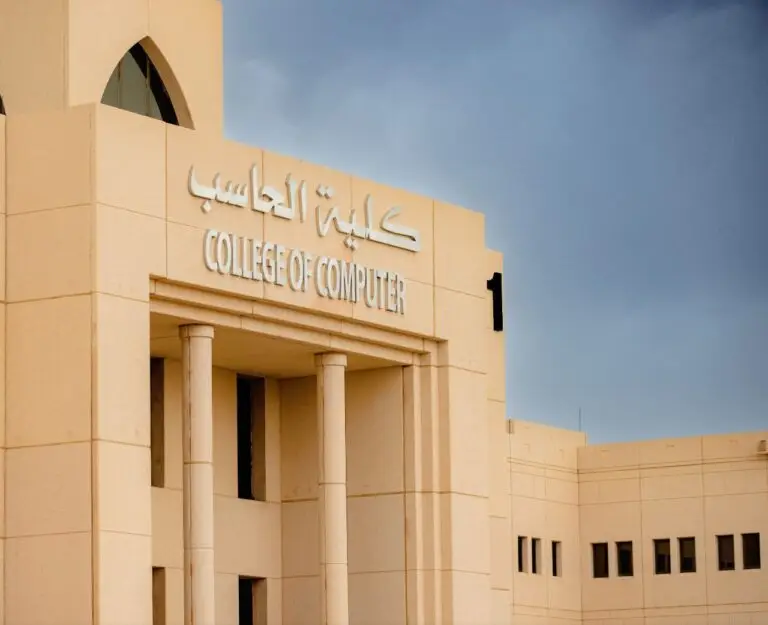 مبنى لون ذا بيج، يتكون من أعمدة ونوافذ مقوسة، تطفوه باللغتين العربية والإنجليزية تحمل اسم "كلية الحاسب" تحت سماء ملبدة الأرنب.