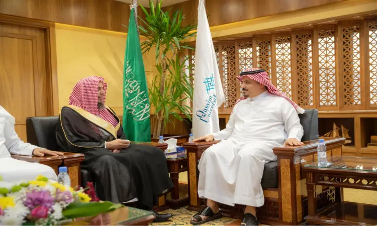 يرتدي رجلان الزي السعودي التقليدي في المكتب الرسمي، وخلفهم أعلام المملكة العربية السعودية بمقرهم العام بالبريدة. ويظهر أنه يرتدي الشماغ السعودي الأحمر مع العقال والبشت السعودي الأسود، بينما يرتدي غترة سعودية بيضاء مع عقال وثوب أبيض. وتزين أمامهم ماء الشرب وترتيب الزهور.