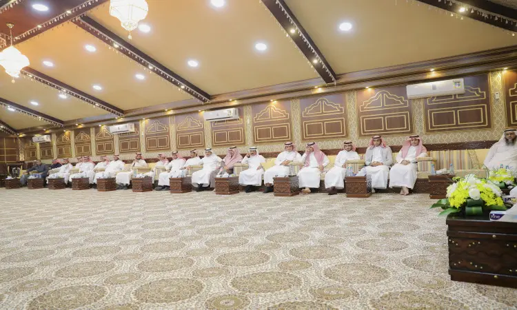 يجتمع جمعٌ من الرجال بزيهم التقليدي الامتداد في الغترة أو الشماغ السعودي والعقال، وقد ارتدى الفرق البشت السعودي، داخل قاعة كبيرة فخمة يغطي أرضها بساط مزخرف وزينها الضوء المضيئة، وذلك لحضور شرف منسوبي الجامعة. يتناول في مقدمة القاعة باقات الزهور بينما يشرف معالي مدير جامعة القصيم على المجريات المجرمين المشاهير يليق بهم.