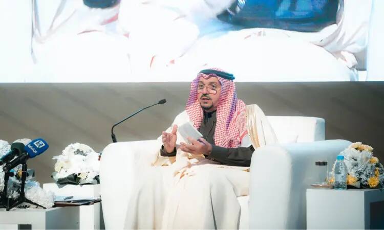 يرتدي الرجل الغترة السعودية والعقال والبشت السعودي على مقعد أبيض ضمن منصة الجامعة، وهو غالبا بحيوية واهتمام. وتحيط به طاولات بجواره تحمل ميكروبات وزهورًا وقوارير الماء، بينما تلتقط خلفه شاشة كبيرة. ومن المحتمل أن يكون هذا الرجل هو صاحب السمو الملكي الأمير الدكتور فيصل بن مشعل بن سعود بن عبدالعزيز أمير منطقة القصيم.