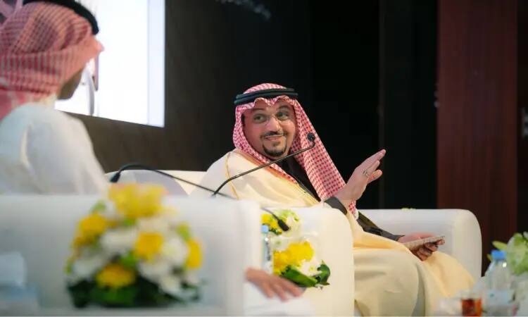 إحدى فعاليات منصة الجامعة، يرتدي رجلان الغترة السعودية والعقال والبشت التقليدية على كراسٍ بيضاء. يتبادلان الحديث حول تجربتي في وسط الحياة حيث سيما. ينضمون للنقاش مبتسمًا وهو يشير إلى ورقة بيده، فيما تزين الطاولة أمامهم بأكياس الزهور وتوضع عليها الميكروفونات لإثراء الحوار والبراز الأكاديمي للفعالية.