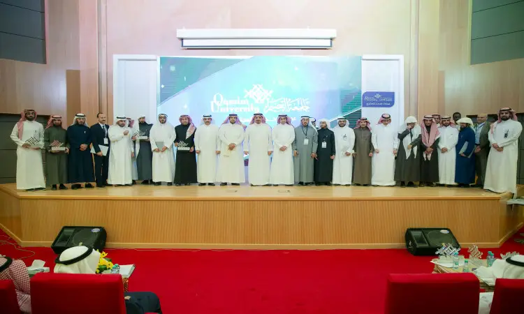 اجتماع كبير من الرجال والنساء على منصة جامعة القصيم، يرتدي الرجال الشماغ السعودي أو الغترة والعقال والبشت السعودي، بينما يرتدى النساء بملابس الشباب، وذلك للمرة الأولى صورة جماعية خلال تكريم خدمة المجتمع في قاعة شرفات مضاءة بشكل جيد.