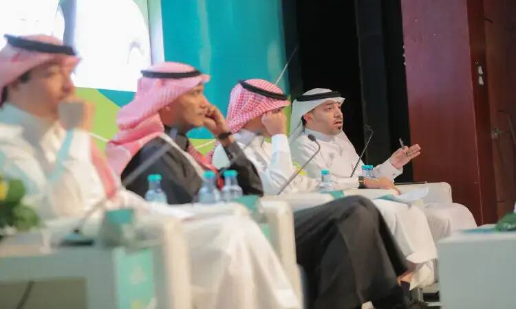 يجلس الرجال الأربعة تحت الغترة أو الشماغ والعقال والبشت السعودي على المنصة في مؤتمر التعصب في القصيم. غالبا ما يتم ذلك عبر الميكروفون، بينما تنتهى باهتمام. أعد تناول الطعام أمامهم زجاجة مياه معدنية وعدة ميكروفونات.