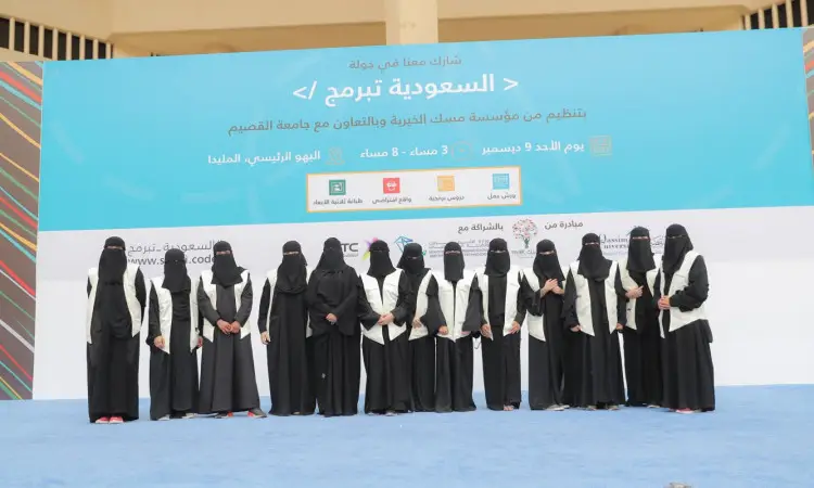 مجموعة من نساء المدينة تتكلمن على التيس في الجامعة في القصيم، وهن يرتدين العباءات السوداء والبشت السعودي، مع تغطية الوجه بالنقاب، ويضع بعضهن الشماغ السعودي أو الغترة السعودية والعقال. وتحمل شعارات وتفاصيل فعالية "السعودية تبرمج"، مكتوبة باللغة العربية.