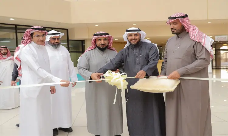 لستة رجال مرتدين الغترة أو الشماغ والعقال، وبعضهم يرتدون البشت السعودي، داخل المدينة الجامعية في القصيم. يقوم بكتابة اثنين منهم بشريط أبيض، في حين تم تسجيل آخر وسادة تحت الشريط، في سيكاراي ميرازِم لافتتاح النجاح أو الجامعة.