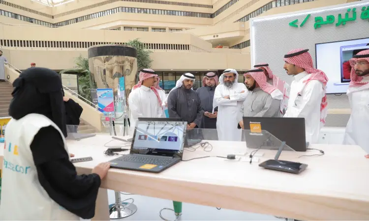 اتصل مجموعة من الرجال مرتدين الغترة أو الشماغ والعقال والبشت السعودي بجانب منصة تقنية في المدينة الجامعية، يستمعون باهتمام إلى سيدة ترتدي عباءة وحجاباً أسود وجلس خلف طاولة عليها أجهزة حاسوب محمولة مفتوحة، حيث يستعرضون لهم إحدى المبادرات التقنية المتميزة على لعبة "السعودية تبرمج" وذلك في بيئة حديثة رائعة التطور الذي تشهده جامعة القصيم.