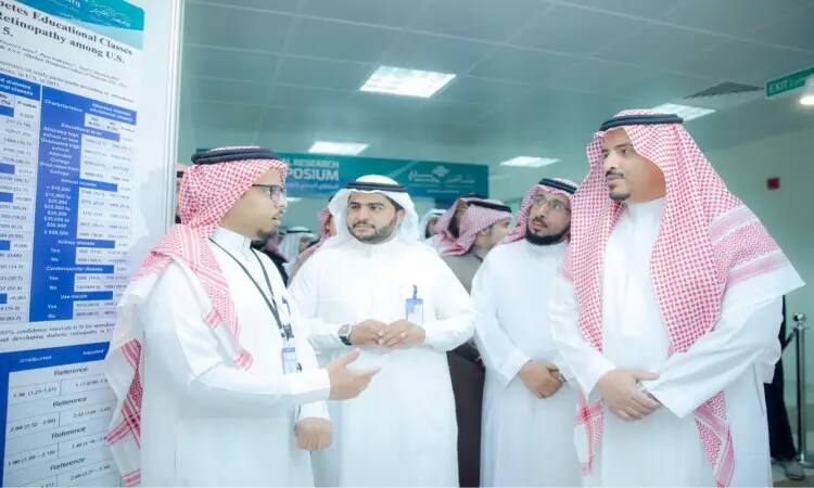 الاتصال عدد من الرجال مرتدين الغترة أو الشماغ السعودي مع العقال، داخل بعضهم يرتدون البشت السعودي، قاعة مغلقة، يناقشون ملصقًا مدروسًا بشكل بسيط من خلال فعاليات الملتقى الطبي. ويضفي الحضور الرسمي لمدير الجامعة وعدد من الشخصيات المرموقة طابعًا أكاديميًا وهندسيًا مميزًا على.