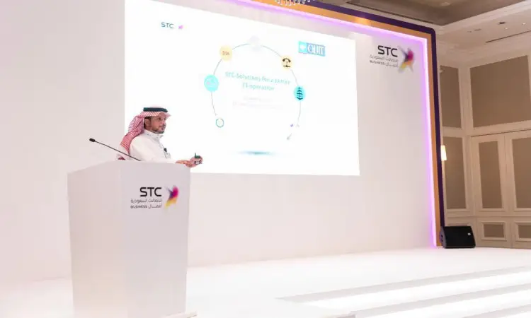 Catman dressed in a Saudi ghutra, aqal, and shemagh with a Saudi besht on a podium with the STC logo, officially showcased at the Dubai Work event, with a screen behind him showing a diagram highlighting the concept of successful engagement.