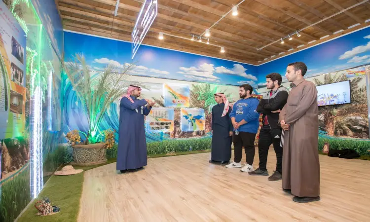 يرتدي رجل غترة سعودية، عقال، وشماغ بالإضافة إلى بشت سعودي بإلقاء عرض تقديمي رسمي حول "الأهمية الغذائية" أمام خمسة من الشباب في قاعة اجتماعات داخل جامعة القصيم. تزين العربة الفاخرة شعارات الشعار الكلاسيكية من الصحراء والواحات، بالإضافة إلى عروضات ثقافية عالمية وشعارات عالمية لمهرجان الجنادرية.