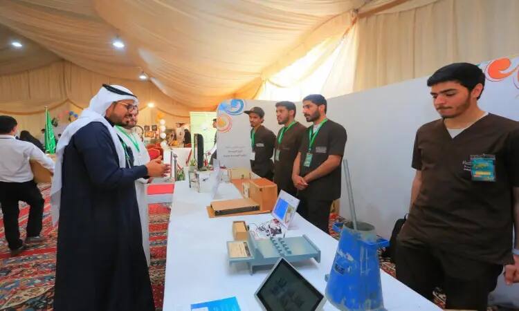 أت مجموعة من الشباب مرتدين غترة أو شماغ سعودي مع عقال، ويضع الفريق بشتاً سعودياً فوق زيهم الرسمي، خلف طاولة عرض المشاريع العلمية خلال المعرض المقام في مخيم الجامعة. ويتفاعلون مع الزوار خلال فعاليات الفعالية ربيعة ربيعة داخل خيمة مضاءة بشكل جيد، في احترام احترام الفنان الرسمي والتنظيم المتميز لجامعة القصيم.