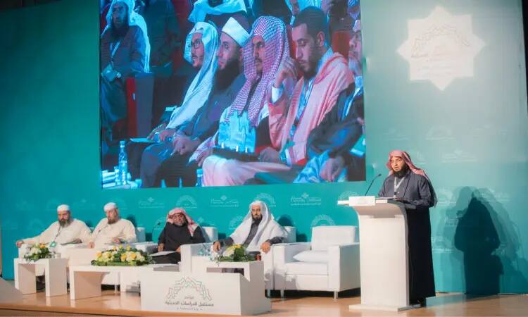 بوضوح لا أحد يقصد مرتدياً الغترة والعقال والبشت السعودي أمام الحضور في مؤتمر الدراسات الحديثة في القصيم، ويجلس إلى جانبه على المنصة أربعة رجال يجلسون الشماغ السعودي والمسؤولة الرسمية. وفي هذه الأثناء، تم عرض صورة كبيرة على الشاشة للمتحدثين أثناء مناقشتهم موضوع الشباكات الطاحنة في السنة النبوية.