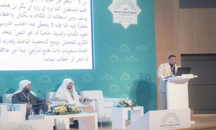 يظهر في الصورة ثلاثة رجال الزي السعودي الرسمي الستة عشر في الغترة أو الشماغ مع العقال، بالإضافة إلى البشت السعودي. يشارك هؤلاء الرجال في مؤتمر الدراسات الحديثة في القصيم؛ حيث يجلس اثنان منهم على المنصة بينما الاتصال الثالث خلف المنصة للقاء كلمته. ويعرض خلفهم شاشة كبيرة تحمل نصًا باللغة العربية حول تدريس العلوم النبوي الحديث، مما يضفي على الهدف هدفًا وهدفًا وهندسيًا رفيع المستوى.