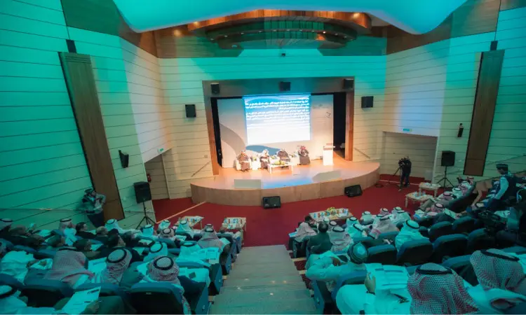تُعقد ندوة أو حلقة نقاش، مثل المؤتمر الدولي حول تطوير أداء الأستاذ الجامعي، في قاعة محاضرات بحضور جمهور غالبيته من الرجال الحاضرين الثوب السعودي مع الغترة أو الشماغ السعودي يعلوه المقال، ويضع الفريق البشت السعودي. اذهب للحضور في مواجهة الوجهين وشاشة كبيرة تعرض نصوصاً ومواد مخصصة بموضوع النقاش.