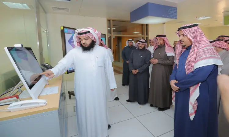 توم مجموعة من الرجال مرتدين الغترة أو الشماغ السعودي مع العقال والبشت السعودي، أحدهم يتفاعل مع شاشة لمس إلكترونية في بيئة حديثة، وذلك في إطار إبراز الخدمات الإلكترونية من خلال عرض توضيحي أو تقديم في جامعة القصيم.