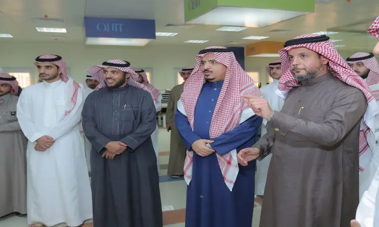 الاتصال مجموعة من الرجال مرتدين الغترة والشماخ والعقال والبشت السعودي في قاعة الملابس مضاءة بشكل جيد، ويتبادلون الحديث الرسمي حول التشفير والخدمات الإلكترونية، وذلك بحضور عدد من الأشخاص ولافتات يرصدون في مشهد مشهدي ضمن فعاليات تقام في جامعة القصيم.