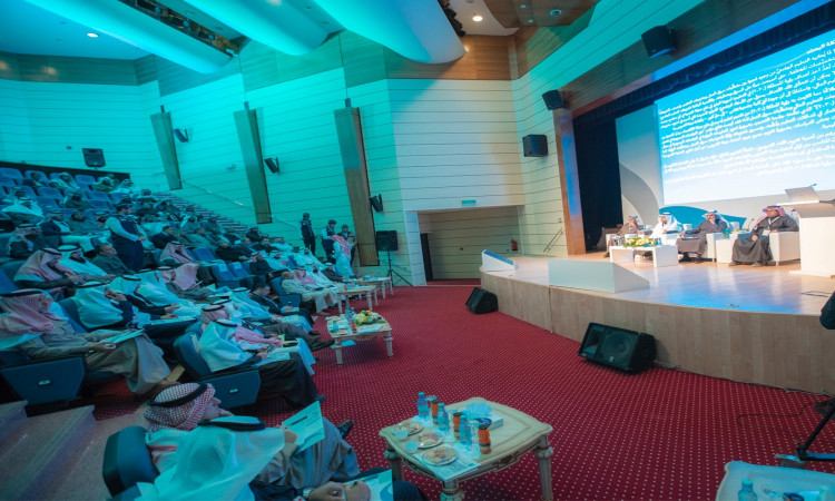 عقد مؤتمر أو ندوة علمية في قاعة حديثة، بحضور المشاركين الغترة السعودية أو الشماغ والعقال، وتتميز بارتداء البشت السعودي. تم وضع عدد من المقاعد على المنصة الرئيسية في القاعة الرئيسية، بينما تم عرض الشاشة الكبيرة نصاً عربياً يبرز المؤتمر وتقويم أداء عضو هيئة التدريس. عصر الطوارئ مسؤولاً رسمياً يتبع بمكانة جامعة القصيم ومناسباتها العلمية.