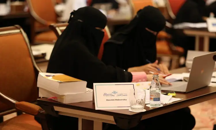 تجلس سيدأتان ترتدي ملابس طويلة على الطاولة أثناء العمل على أوراق وجهاز الكمبيوتر المحمول، وتوضع أمامهما مجموعة كبيرة من الكتب والزجاجات، إلى جانب غير مضمون تحمل اسم "جامعة القصيم". جاء ذلك خلال مسابقة الملصقات البحثية المصاحبة لمؤتمر سيفا 2019. شارك في المكان عدد من المشاركين مرتدي الشماغ السعودي والعقال والبشت، بما في ذلك الطابع الرسمي والهوية الوطنية التي تتميز بالجامعة وفعالياتها.