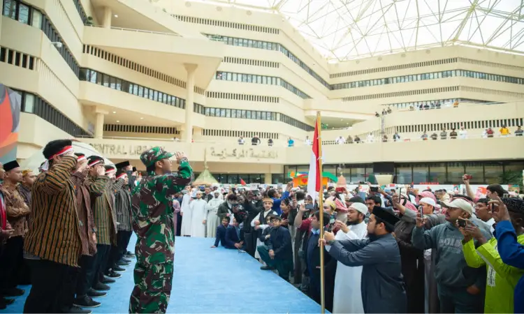 أقصى عدد من الحضور، من بينهم رجال الزي وآخرون بلباس تقليدي متمثل في الغترة أو الشماغ العسكري والعقال والبشت السعودي، يؤدون التحية على منصة زرقاء خلال "مهرجان تراث الشعوب"، وذلك بحضور مدير جامعة القصيم ومشاركة أكثر من 20 دولة. وقد تابع هذا الحدث جمع غفير من الحضور الذين أكدوا الفعاليات بقاطع الصور من عدة شرفات.