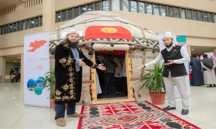 يرتدي رجلان الزي القومي الكيرغيزي إلى جانب يورت مزينة تحمل علم قيرغيزستان، مرحّبين بالزوار في مهرجان تراث الشعوب ليتعلموا حضارات مصادرهم. مكان وسجادة حمراء ذات نقوش مميزة وعدد من النباتات المحفوظة اقرأاً من الفخمة على الرحبة والعصرية للعصر. وقد استمتع من المملكة العربية السعودية بمظهرهم الرسمي بارتداء الغترة أو الشماغ السعودي مع العقال والبشت السعودي، بما في ذلك مع الفارس الرسمي لجامعة القصيم.