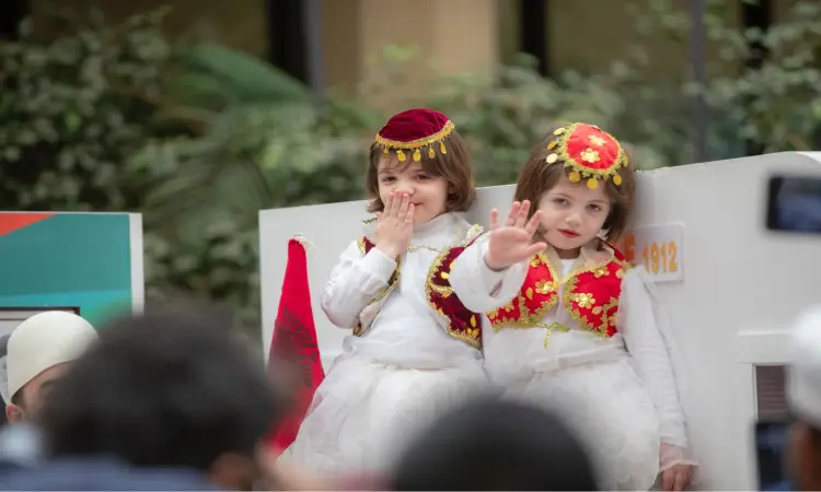 أت طفلان صغيران جنباً إلى جنب، ارتديين البشت السعودي والغترة مع الشماغ والعقال، وذلك من خلال مشاركتهما في مهرجان تراث الشعوب في القصيم؛ حيث يظهر وهو يلوح بيده، بينما يقوم الآخر كما قبلة، ويحيط بهما مشهد من الخضرة في الخلفية.