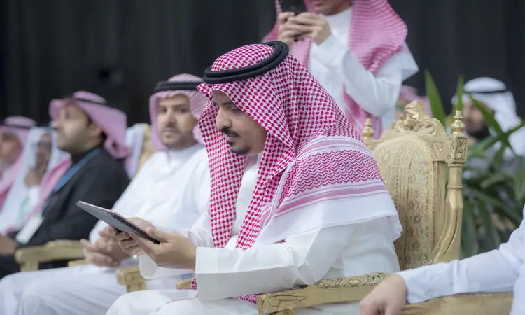 يرتدي الرجل الزي الرسمي السعودي، متشحًا بالكغترة والعقال والبشت سعودي، يجلس على كرسي ويفخم تصفح جهاز لوحي خلال أول مناسبة في قاعة الملابس الداخلية؛ ومن المحتمل أن يكون مدير الجامعة. كما يظهر بجواره عدد من الرجال الآخرين الذين غفلوا عن الشماغ أو الغترة السعودية، منشغلين بهواتفهم أو يتبادلون أطراف الحديث. يُعتد بالفعالية بندوة البحث عن الصيدلي ضمن فعاليات جامعة القصيم.