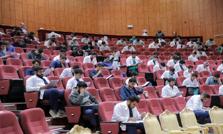 وأظهروا أنهم يجلسون في قاعة محاضرات الاجتماعات المتنوعة ذات الاختصاص، يشاركون بجدية في أوراقهم أثناء أداء اختبار قياس المستوى. وتحمل معظمهم المعاطف الطبية البيضاء، ما يدل على أن الاختبار يرتبط بتخصصات طبية أو علمية ضمن كليات الطب في جامعة القصيم. ويبرز بين تلاميذ الغترة السعودية أو الشماغ مع العقال، كما أظهر بعض الأساتذة وهم ينتظرون البشت الرسمي السعودي، مما يعكس اتباع قواعد التنظيم مع تقاليد وهي المملكة العربية السعودية.