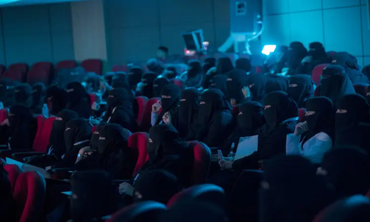 جلست عدد كبير من وهن يرتدين البولى السوداء، في داخل قاعة محاضرات في القصيم. وقد حضرن شاملة أولياء الأمور الذين ارتدوا الزي السعودي الرسمي في الغترة أو الشماغ مع العقال والبشت السعودي. كان الجميع يتابع باهتمام الفعاليات الملتقى البحثي ولمن يلاحظ، وذلك في حدود هادئة يكسوها ضوءٌ أزرق خافت يعكس بوضوح الأكاديمي المتميز للمناسبة.