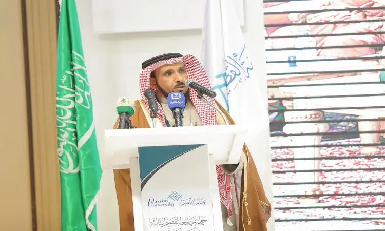 الرجل مرتدياً غترة سعودية وعقالاً وبشتاً سعودياً أمام منصةٍ، بعد ميكروفونات، وشعارها جامعة القصيم. ويبرز خلفه كل من علم المملكة العربية السعودية وعلم أبيض آخر، في مشهد يجسد جهود الجامعة التوعوية في محافظة ضرية.