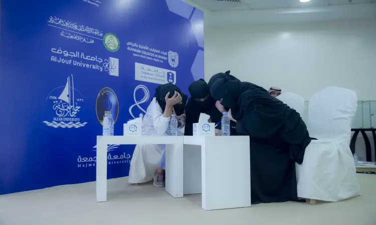 جلست أربعة أشخاص حول طاولة تتوزع عليها مجموعة المياه؛ ثلاثة منهم كذبت العباءات السوداء، بينما يرتدي الثوب الأبيض مع الغترة السعودية والعقال، ويضع فوقهما البشت السعودي. فيما بينها حديثًا رسميًا في القانون العلمي، وخلفهم خلفية خضراء تحمل نصوصًا باللغة العربية والإنجليزية حول التوجهات الحديثة في ملتقى طب الأسنان، إلى جانب شعارات جامعة القصيم والجهات المشاركة.