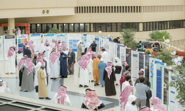 يجتمع جمعٌ من الناس، يغلب عليهم الشباب السعوديون مرتدون الغترة أو الشماغ السعودي مع العقال والبشت السعودي، وذلك في قاعة في القصيم، حيث يتبادلون النقاشات ويطّلون خلال الملصقات العلمية ملتقى لجنة الدراسات العليا العليا.