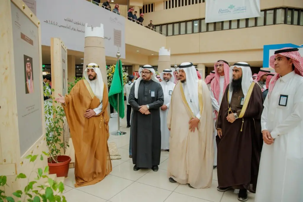 الاتصال مجموعة من الرجال مرتدين الغترة أو الشماغ مع العقال والبشت السعودي في مكان مغلق ضمن فعاليات معرض يوم بدينا في جامعة القصيم، وهم يتأملون باهتمام لوحة عرض تتوسطها صورة شخصية. وأحد أهم أعضاء اللجنة هو اختيار أبرز أعلام المملكة والعناصر الثقافية الهامة للمنظمات الأساسية في الجامعة.