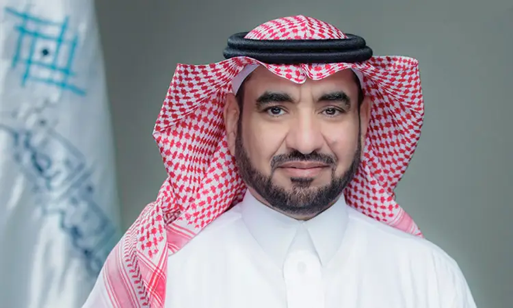 أترخخ، رئيس جامعة القصيم، ارتديا الثوب السعودي الرسمي مع شماغ سعودي وعقال، ويعلوه بشت سعودي فاخر. يظهر أمام علم باريس، مبتسماً ابتسامة واضحة تجاه الكاميرا.