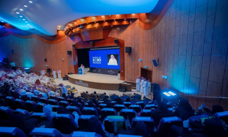 يتخصص في الجامعة الكبرى بالحضور بينما يُلقي رئيس الجامعة، مرتدياً اغترة وشماغ وقال وبشت سعودي رسمي، كلمته من على المنصة. وتتصدر هذه الشاشات صور المشاهير في عام 2030 وصورة أحد الشخصيات. وتتميز بطابعها العصري مع الكسوة الخشبية والإضاءة الزرقاء، مما يبرز المساهمات التطوعية في جامعة القصيم.