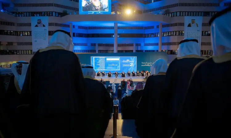مجموعة من الأشخاص تولي الزي السعودي الكلاسيكي في الغترة أو الشماغ والعقال والبشت السعودي يصعدون السُلّم نحو المسرح الكبير خلال الطلاب الجدد في قاعة حديثة مُضاءة الأزرق، بحضور جمهور غفير وشاشات بارزة ولافتات عربية، بالإضافة إلى تشيف سمو أمير منطقة القصيم.