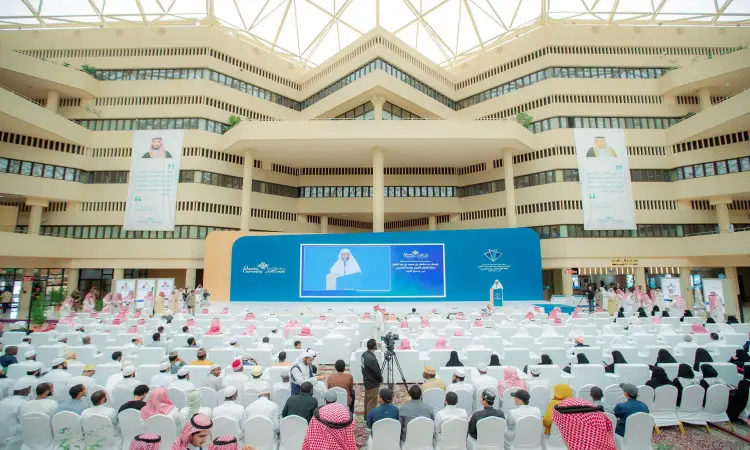 مايك فعال كبير في جامعة القصيم، حيث حضر جلسة في مساهميه وهم ظلموا الغترة السعودية أو الشماغ مع العقال والبشت السعودي، ويواجهون المنصة الرئيسية. وعلى المنصة وقف صاحب السمو أمير منطقة القصيم ملقيًا كلمته من على منصة الخطابة، وخلفه تحمل لوحات شعار مسابقة حفظ القرآن الكريم. أُقيم الحدث في ردهة التصميم الحديث تزيّنها التغييرات الداخلية.