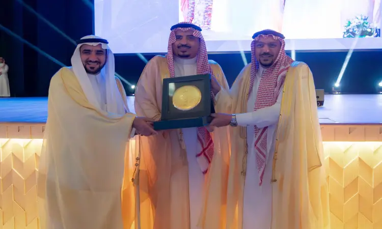 خلال الدورة الرسمية، وقف ثلاثة رجال مرتدين الغترة أو الشماغ مع العقال والبشت السعودي على المنصة، وهم يبتسمون ويحملون لوحة ذهبية كبيرة داخل صندوق عرض فاخر. وقد شهد حضور سمو الأمير منطقة القصيم، وتكريم رئيس الجامعة وسط الحضور وإضاءة وحضور الجماهير خلفهم.