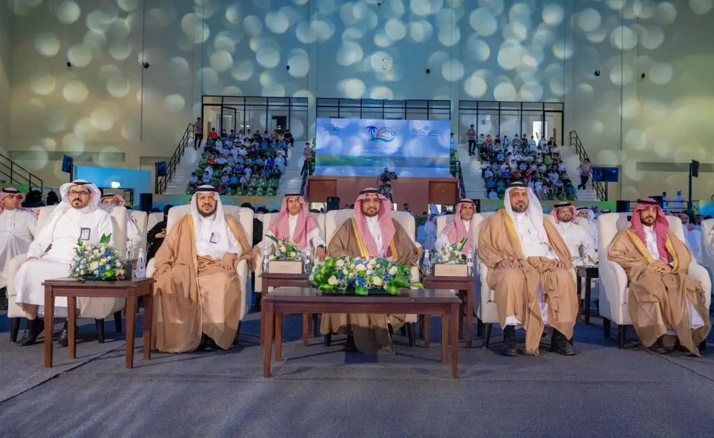 مجموعة من الرجال الحضور الغترة أو الشماغ والعقال، بالإضافة إلى البشت السعودي، في الصف الأمامي لأحد الفعاليات الرسمية المقامة داخل القاعة من جامعة القصيم ضمن فعاليات النادي الصيفي السابع. وتزين الجداول أمامهم تنسيقات الزهور، بينما يظهر في الخلف جمهور كبير يقدر عليه 45 ألف مستفيد.