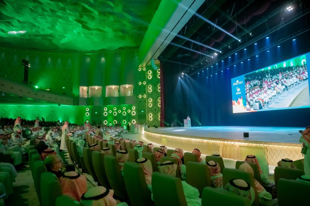 امتلأت القاعة الحديثة في جامعة القصيم بجمهور كبير غالبيته من الرجال مرتدين الشماغ والعقال والبشت السعودي والغترة، وقد أضيئت القاعة بإضاءة خضراء أثناء حضور كلمة أمير منطقة القصيم على المنصة، فيما عُرضت فعاليات اليوم الوطني 94 على الشاشة الرئيسية.