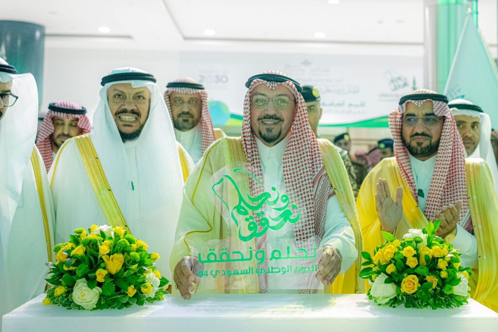 الاتصال مجموعة من الرجال السعوديين مرتدين الغترة أو الشماغ والعقال والبشت السعودي، مبتسمين خلف طاولة تزينها تنسيقات الزهراء القديمة ولوحة خضراء تحت في باليوم الوطني في جامعة القصيم. ساهم في خلفية رؤية السعودية 2030.