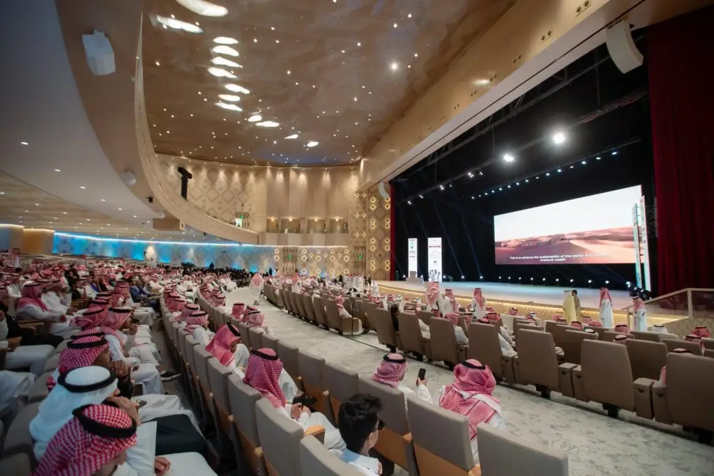 امتلأت الجامعة الكبرى في جامعة القصيم بالحضور الذين ارتدوا الشماغ السعودي والغترة السعودية، وجلسوا متجهين نحو المنصة الرئيسية حيث يقام اللقاء العلمي الدولي الثاني للإبل. وقد تم منحها جواز السفر الأصلي الذي تم منحه مني إلى إضاءتها بالكامل، في حين تم عرضه على الشاشة الرئيسية مشهد طبيعي يعكس الطبيعة النيجيرية.