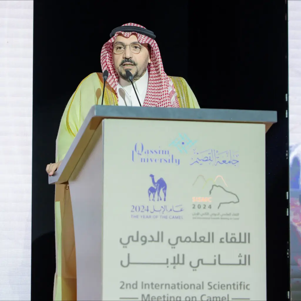 رجل غالبا مرتديا الثوب والشماغ السعودي التقليدي من منصة الخطابة خلال اللقاءات العلمية الدولية الثانية للإبل في جامعة القصيم. لتناول الطعام على المنصة شعارات الجامعة والفعالية، ويحضر هذا الأمر وبعد صاحب السمو أمير منطقة القصيم، بالتأكيد على أهمية الإبل ومكانتها في المجتمع العلمي والثقافي.
