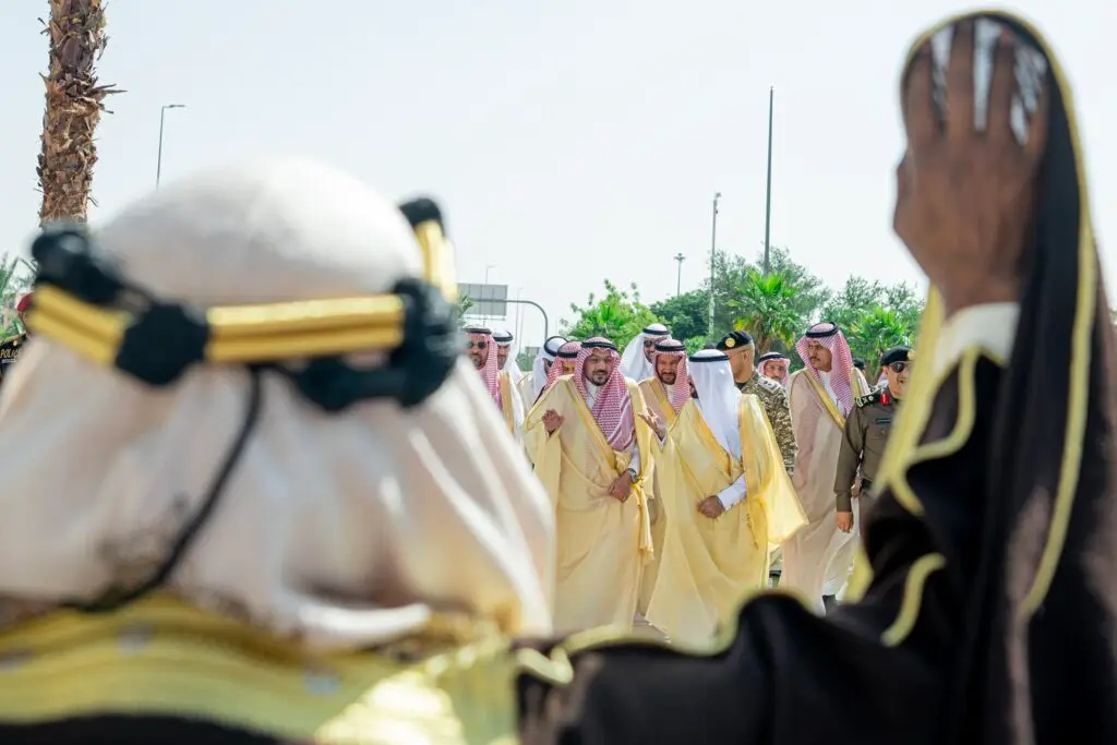 مجموعة من الرجال الزي السعودي التقليدي، بما في ذلك في ذلك صاحب السمو أمير منطقة القصيم، ويشوكون مع عدد من في الهواء الطلق. وفيه يرفع أحد الأشخاص للترحيب. مملوكة للمستثمرين النخيل وصف السماء دلالة على ما يتمتعون به جامعة القصيم من بيئة تشجيعية تشجيعية.