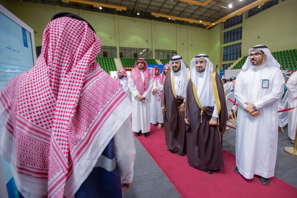 مجموعة من الرجال تحت الغترة أو الشماغ والعقال، إضافة إلى البشت السعودي، يتقدمهم معالي رئيس الجامعة، الاتصالون على سجادة حمراء من خلال أول قيمت داخل مغامرة. ويتبادلون الحديث مع أحد الحضور الذي يرتدي اللباس التقليدي السعودي. ويبرز في المكان الأخضر والسقف الجماعي، وذلك ضمن برنامج فعال للعطاء للطلبة في جامعة القصيم.