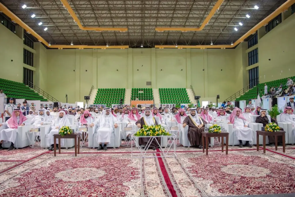 جلسة جمع كبير من الحضور، معظمهم من الرجال بالزي السعودي التقليدي مع الشماغ أو الغترة السعودية، على كراسٍ مربعة في صفوف داخل قاعة فسيفساء ذات خضراء. وذلك خلال استقبال رئيس جامعة القصيم للدراسة الشاملة ضمن فعاليات برنامج "العطاء" الذي يشكل تنظيماً مختلفاً وزخرفياً جميلاً.