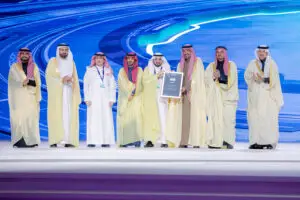 وقف عدد من الرجال مرتدين الشماغ أو الغترة السعودية بالإضافة إلى البدلات الرسمية على منصة الاحتفال، حيث كان الصراع درعاً يتذكرها، وذلك أمام خلفية رقمية زرقاء تتكاملات جامعة القصيم في مجال التحول الرقمي.