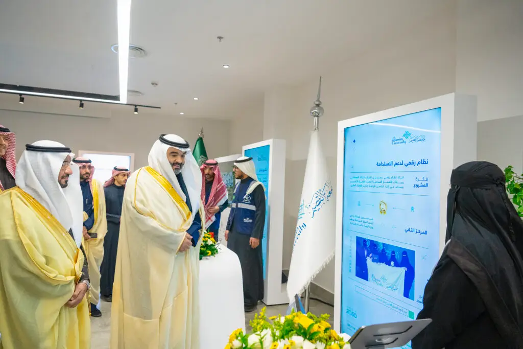 يظهر في الصورة عدد من الرجال تولى الزي السعودي التقليدي، من ضمنه الشماغ أو الغترة السعودية، بالإضافة إلى سيدة ترتدي ملابس بيضاء، وهم يطالعون شاشة رقمية من خلال فعالية تجري عنى بالبحث عن آيات. وتتضمن هذه الصورة الخلفية جامعة القصيم والعلم السعودي وعدد من الملصقات التعريفية.