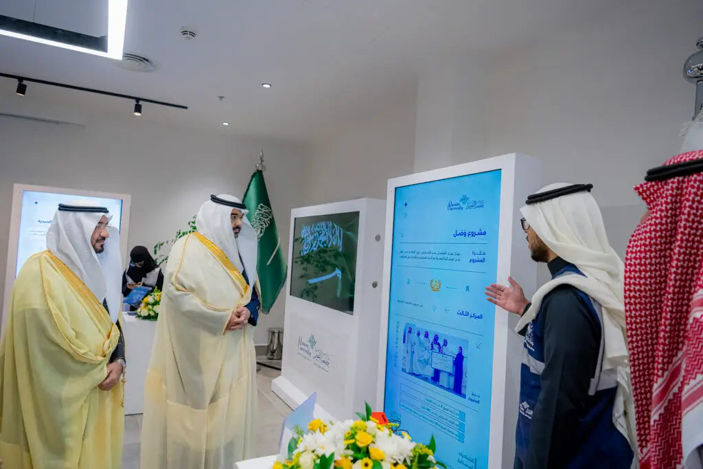 توم عدد من الموجودين، ينتظر الشماغ السعودي والزي التقليدي، يتقدمهم معالي وزير الاتصالات، عرضاً رقمياً في قاعة حديثة تتصدرها راية المملكة العربية السعودية. ويبرز على التنسيق المجاورة تنسيقٌ يُجسد الاهتمام بالبحث الشامل في رحاب جامعة القصيم.