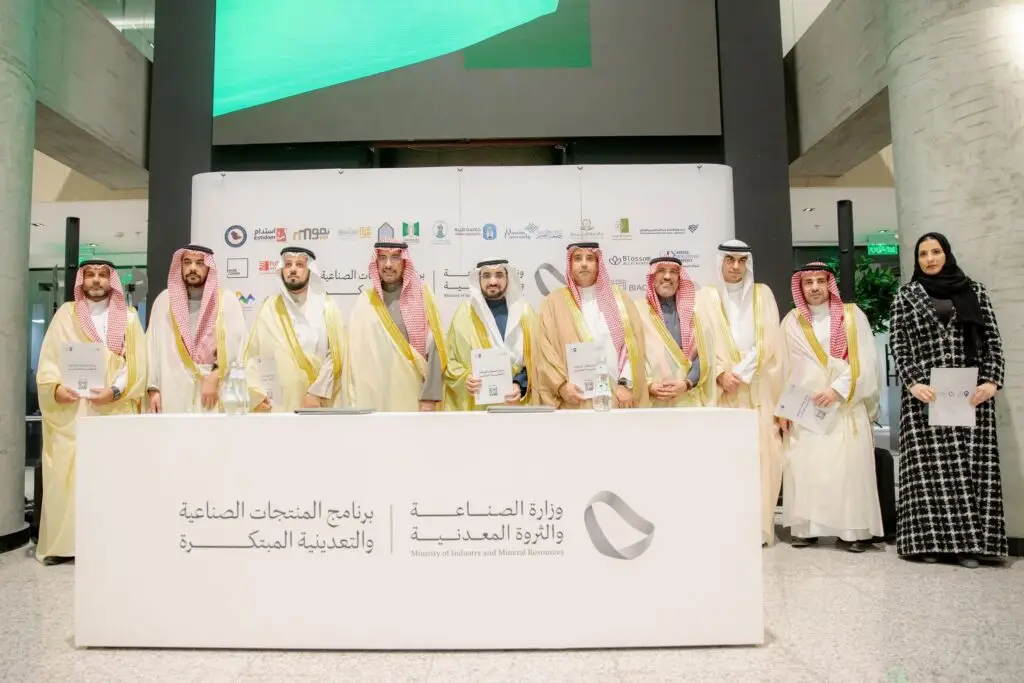 وقف عدد من الرجال مرتدين الزي الرسمي السعودي الامتداد في الشماغ أو الغترة والقالب، بالإضافة إلى جزء منهم فتاة بفستان أسود، خلف قائمة بيع عدد من الملفات، في تُبرز دعم المبتكرين وتطوير الصناعة. المساهمة في شعار وزارة الصناعة والثروة المعدنية باللغتين العربية والإنجليزية.