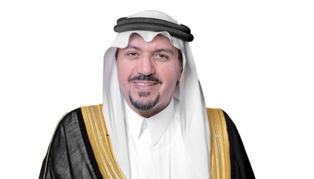 رجل يرتدي الزي السعودي التقليدي ويشبه أمير منطقة القصيم، القط يبتسم أمام خلفية سوداء بسيطة. تظهر بملابس التخرج في جامعة القصيم، مرتديًا ثوبًا نسائيًا أبيض وبشتًا سعوديًا أسود مزين بتطريز ذهبي، بالإضافة إلى غترة سعودية بيضاء مثبتة بعقال أسود.