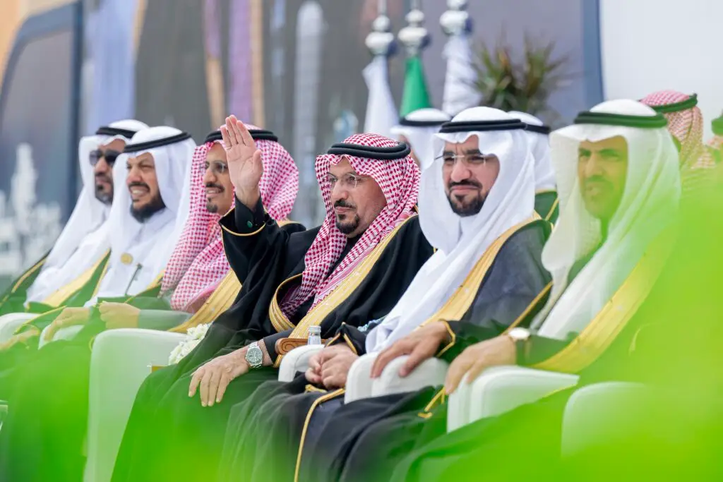 اعتصام مجموعة من الرجال بزيهم السعودي التقليدي، ومن بينهم خريجون من جامعة القصيم، في الهواء الطلق؛ حيث يوصف بأنه بالتحية وهو في المنتصف بينما يتابع الآخرين بالانتباه. البحث عن وسائل الإعلام والمساحات الخضراء في الخلفية، مما يضفي على المواد المتنوعة طابعًا آمنًا ورسميًا.
